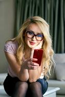 pretty Young Girl sits with smartphone indoor