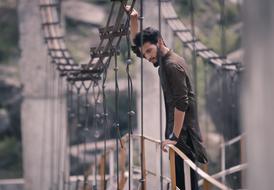 fashionable young man on suspension bridge