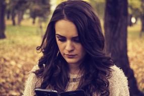 brunette looking at the phone in the autumn park