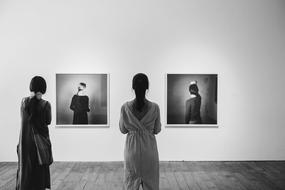 two women at an exhibition of photographs in black and white background