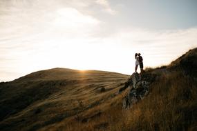 Couple, kissing on the beautiful and colorful mountains, at colorful sunset