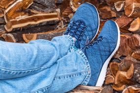 Close-up of the blue shoes on the legs of the person, near the colorful wood