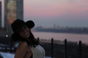 beautiful woman with hat in the city at dusk