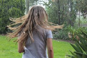 Blonde girl among the green plants under rain