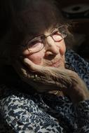 Portrait of the smiling, old woman with glasses, in light