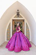 Beautiful and colorful girl in the beautiful, patterned, purple dress, on the QuinceaÃ±era, near the building