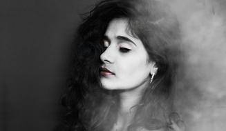 Black and white portrait of a woman with closed eyes and red lips, among the smoke