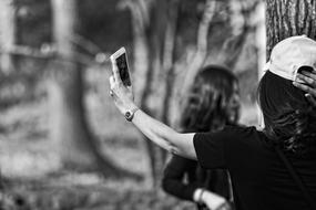 Black and white photo of the person in cap, taking a photo, near the girl