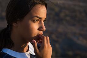 Portrait of the beautiful girl with the fingers on the mouth, in light