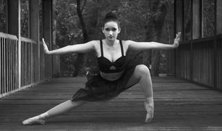 Black and white photo of the ballerina dancer woman, in black dress, on the bridge