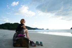 woman on a log on a sandy beach