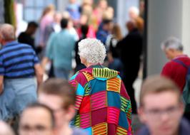 photo of an elderly woman in a multicolored coat on a city street