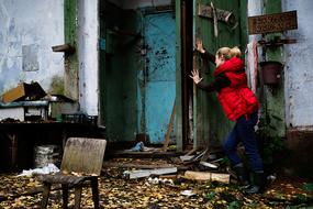 Blonde girl, in the old, colorful building, in the forest