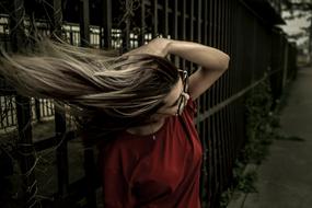 Girl in glasses and red, t-shirt, shakes her head, outdoors