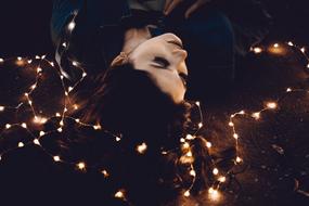 young Woman lying down on ground among lights