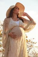 pregnant woman in beige dress and hat