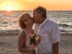 newlyweds with a bouquet on the beach at dusk