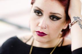 Portrait of the woman with nose piercing, tattoos and bracelet