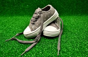 kids sneakers on green carpet