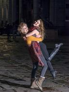 two young happy girls hugging on street at dusk