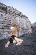 young girl sits on ground at aged wall