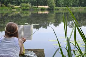 young Woman Reading book at pond