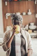 woman with glasses drinks coffee from a yellow mug, kenya