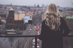 evening photo of a blonde standing on a balcony