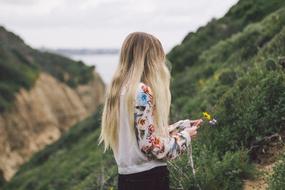 blonde collects flowers on the mountainside