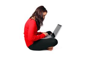 Side view of the girl, typing on the laptop, at white background