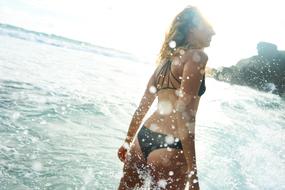 girl in bikini in splashes of water on the ocean