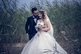 Happy couple in engagement, walking among the green plants