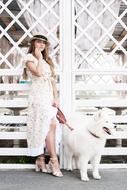 girl in white posing with a dog