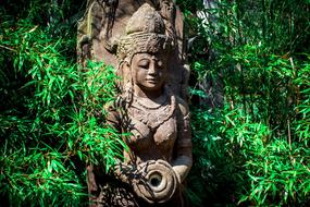 Beautiful statue of the Goddess, among the green plants in India