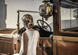 photo of a girl with a beautiful hairstyle on the background of a golden retro car