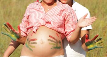 Pregnant woman and man, with the colorful handprints on the belly