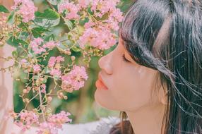 young woman smelling pink flowers
