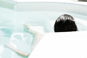 Back view of a woman, sitting in the beautiful, white bath