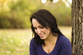 beautiful brunette near a tree on a blurred background