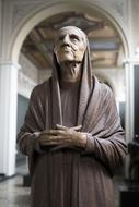 Sculpture of the religious woman, near the colorful arch of the building