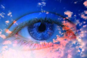 Close-up of the beautiful iris eye, in blue and red sky with the clouds