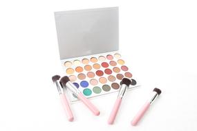 photo of palette of eyeshadows and makeup brushes on a white background