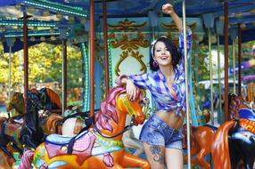 Beautiful, smiling woman with the tattoos, posing on the colorful carousel
