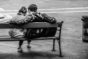 Black and white back view of the couple, sitting on the bench, on the street