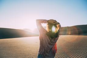 Back view of the girl posing among the beautiful desert in light on landscape