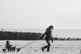 mother pulling sled with Baby in countryside