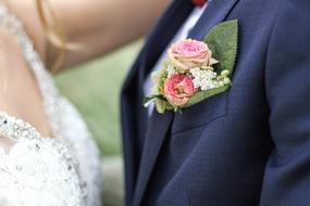 White dress on the bride and colorful and beautiful flowers in the pocket, of the blue jacket of the groom