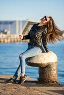 girl with fluttering hair in sunglasses on the embankment