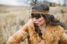 brunette in a red fur coat on a rural field