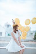 Happy young girl in party hat sits with Balloons